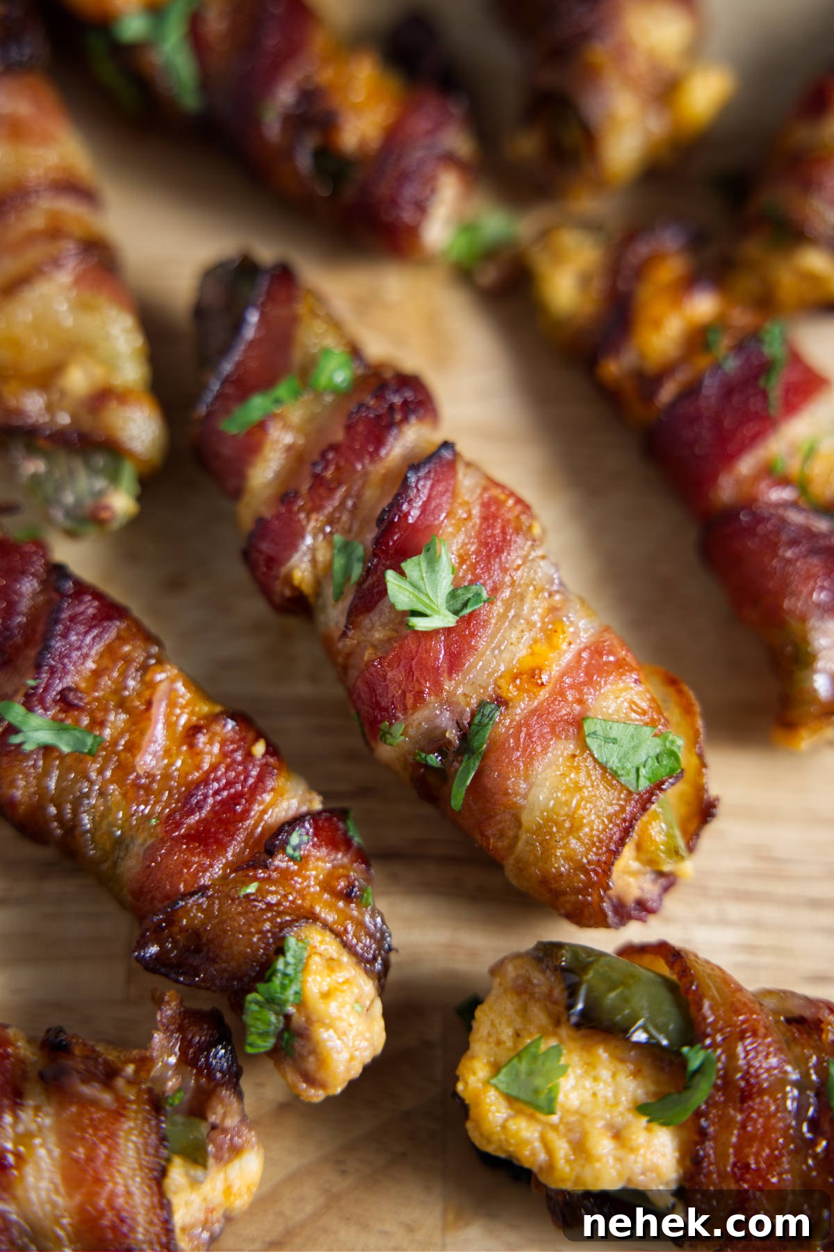 Several bacon wrapped jalapeño poppers on a cutting board.