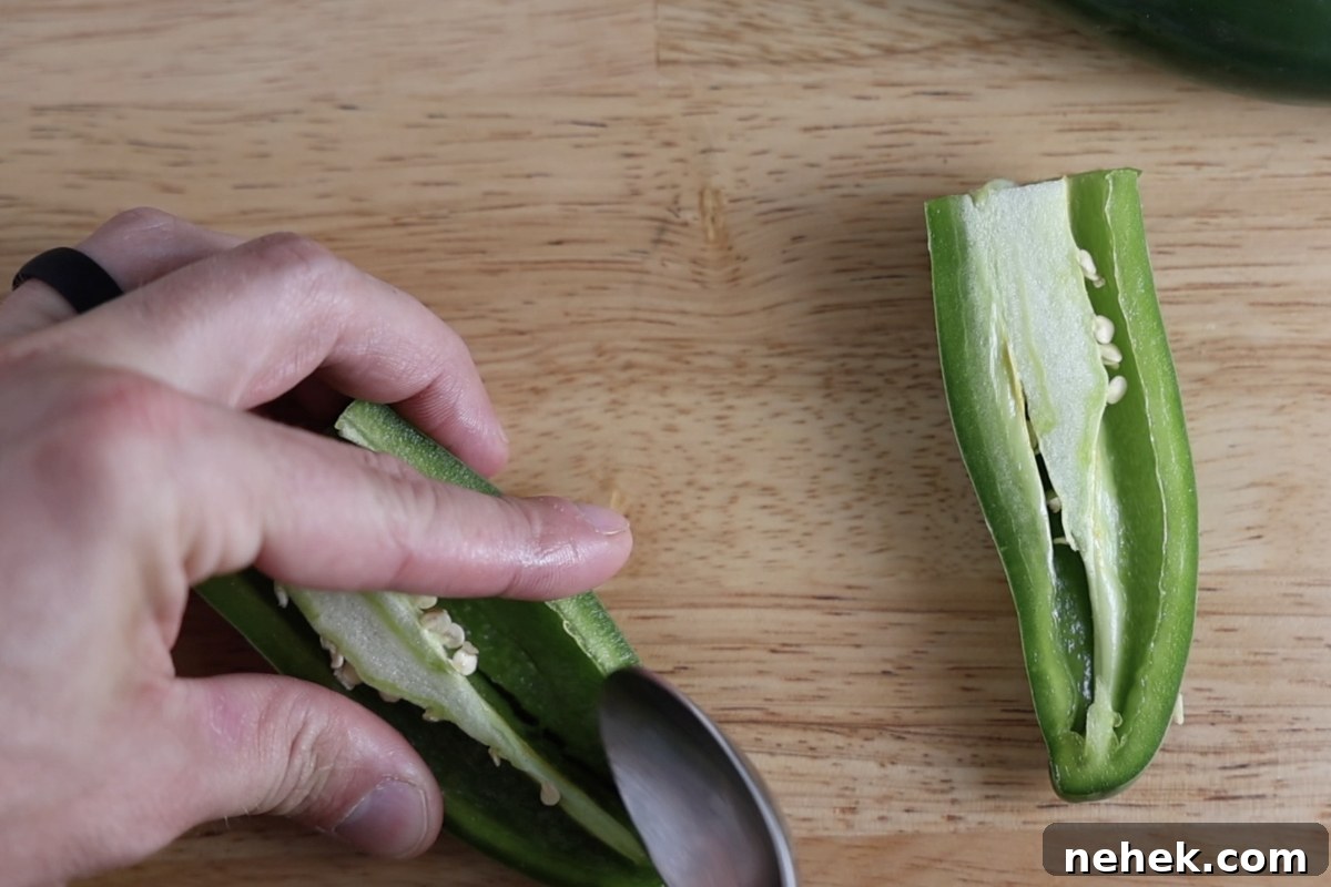 Removing the seeds and ribs from a jalapeno that has been sliced in half.