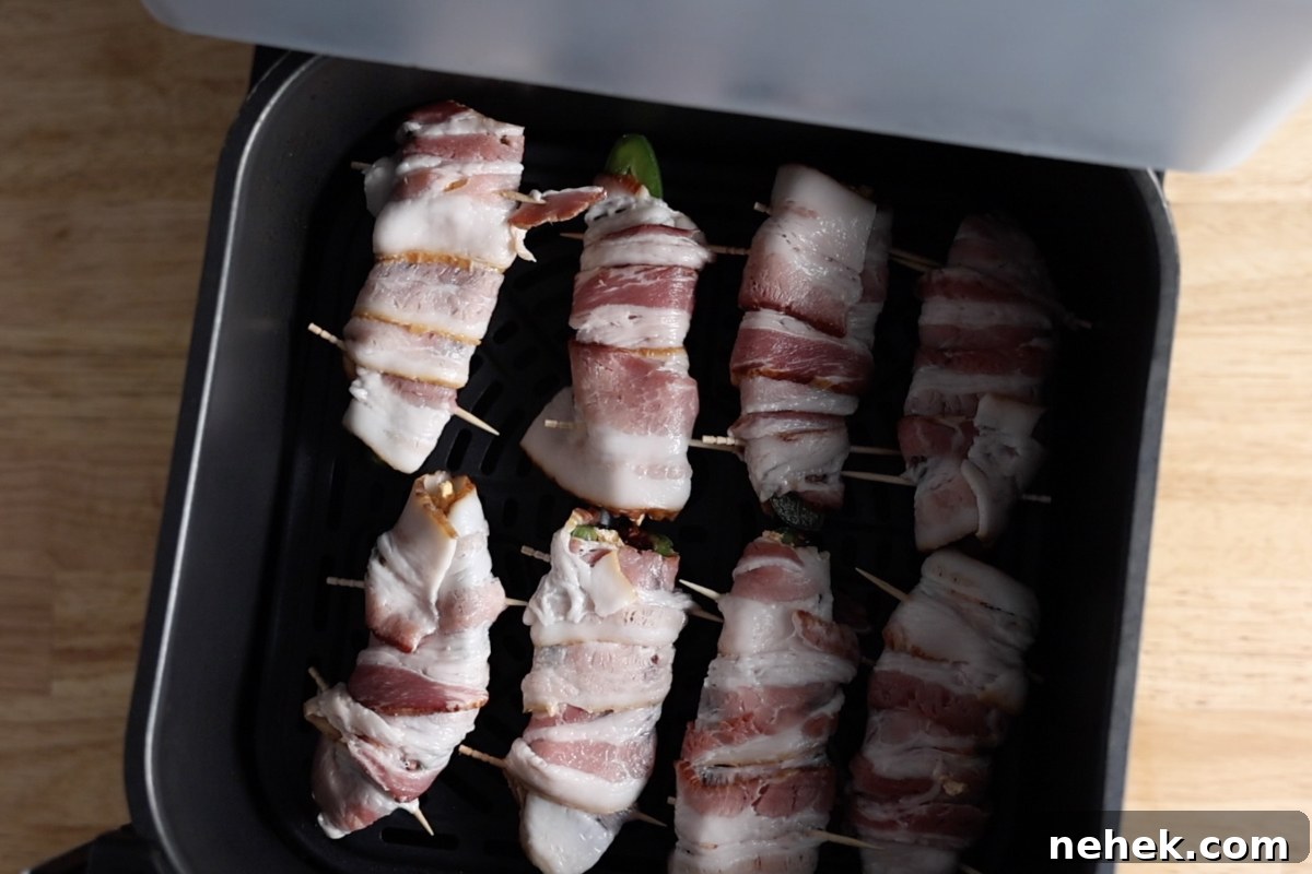 Cooking air fryer bacon wrapped jalapeno poppers in an air fryer.