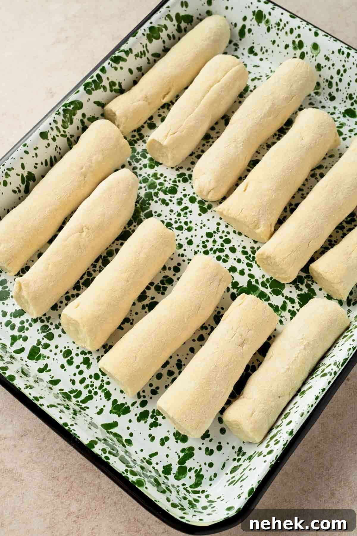 doughy breadsticks on a baking sheet ready to be coated in cinnamon sugar.