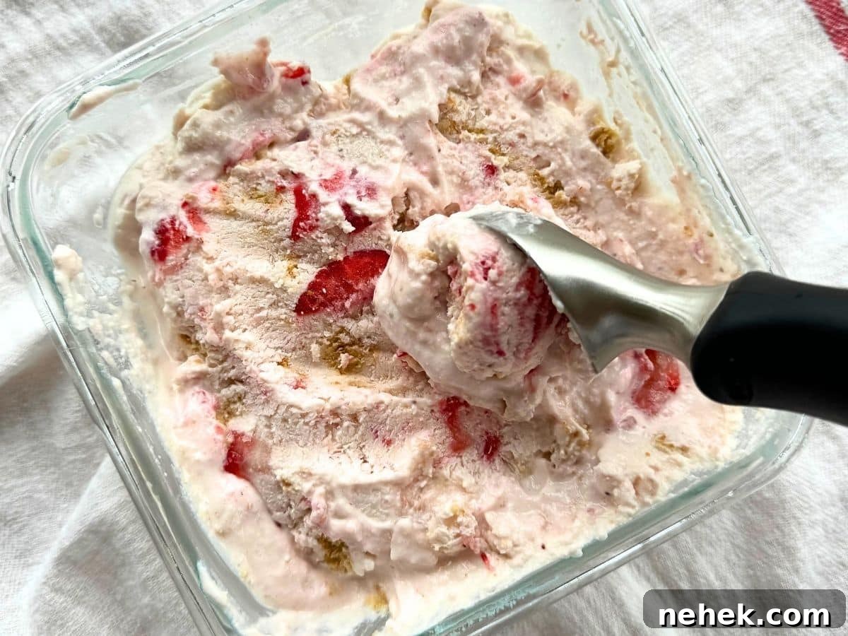 Scoop removing strawberry cottage cheese ice cream from a square glass container.