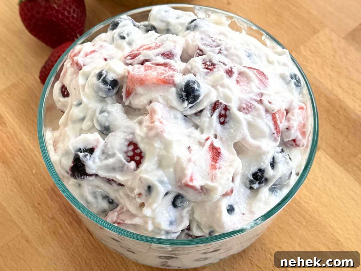 Whipped cottage cheese mixed with blueberries, strawberries, and blackberries in a glass bowl.