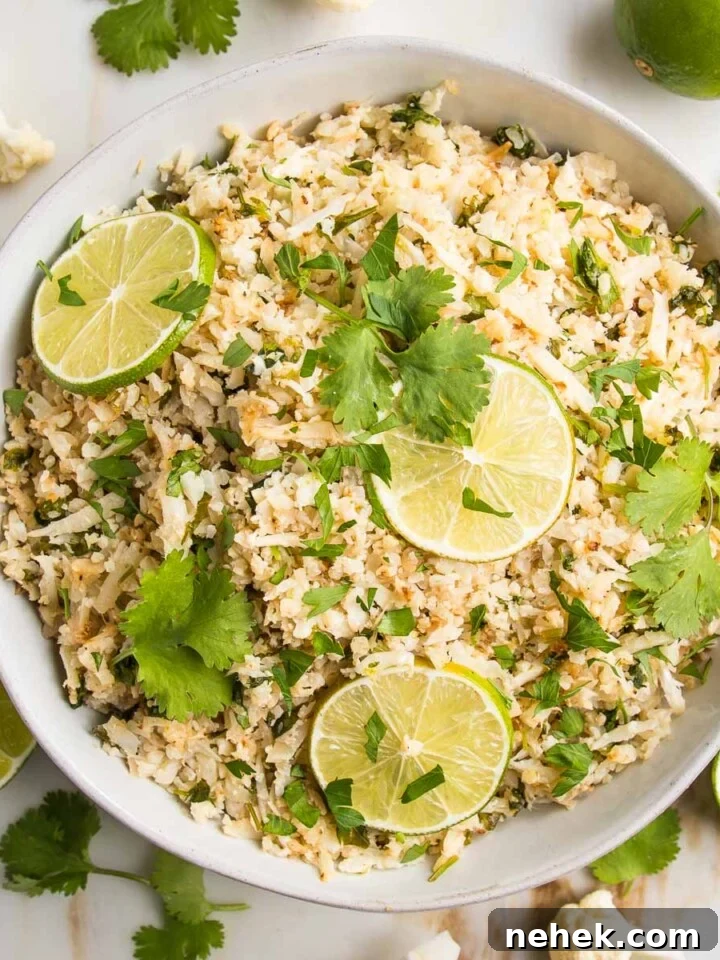 Cauliflower Rice with lime slices and cilantro in a white, low shallow bowl.