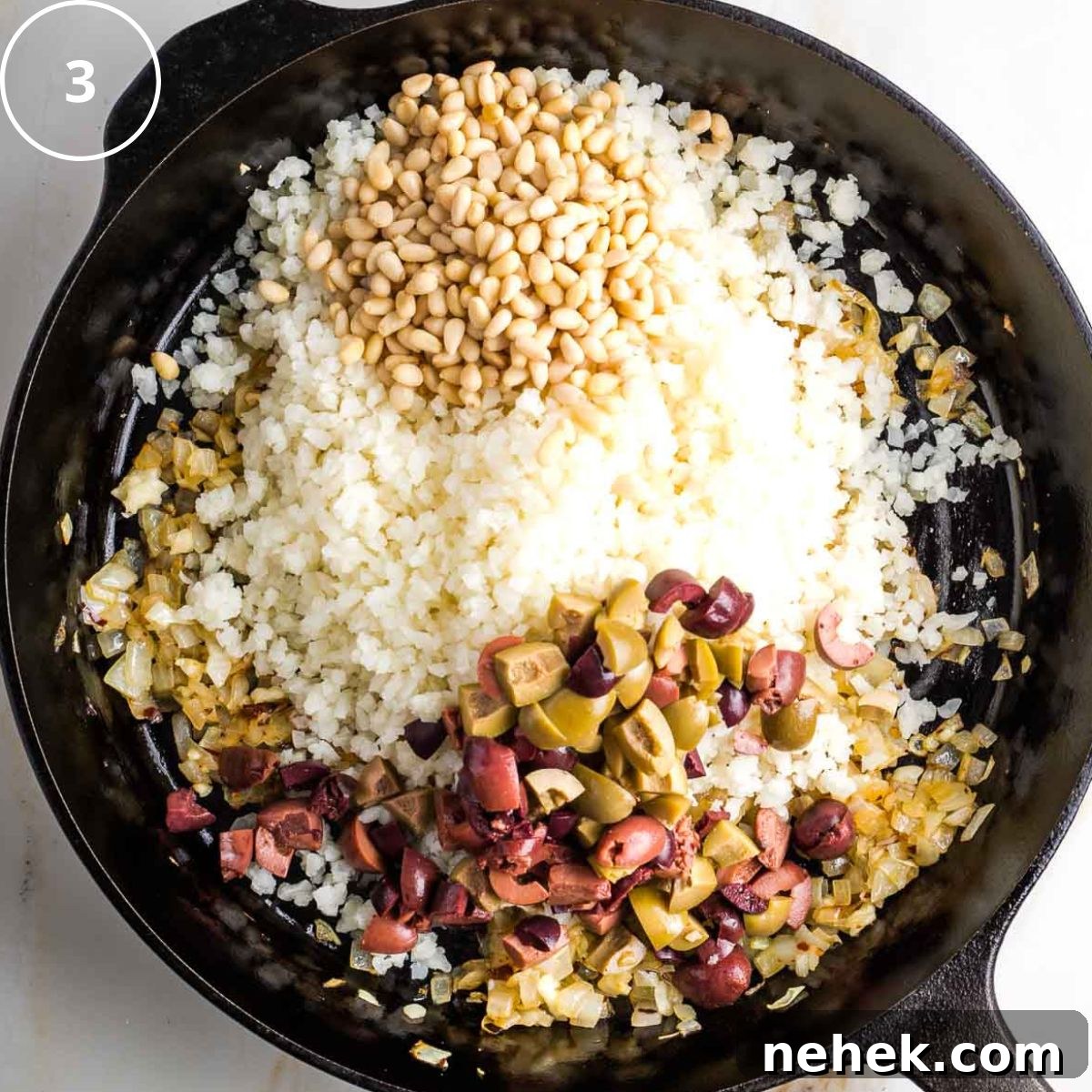 Mediterranean Cauliflower Rice Recipe with Sun‑Dried Tomatoes & Olives 6 Step 3: Cast iron skillet with riced cauliflower, chopped olives and pine nuts over satueed onions.