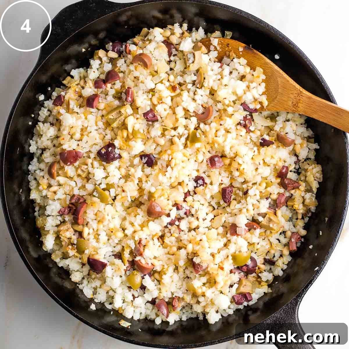 Mediterranean Cauliflower Rice Recipe with Sun‑Dried Tomatoes & Olives 7 Step 4: Mediterranean cauliflower rice with olives and pine nuts in a cast iron pan.