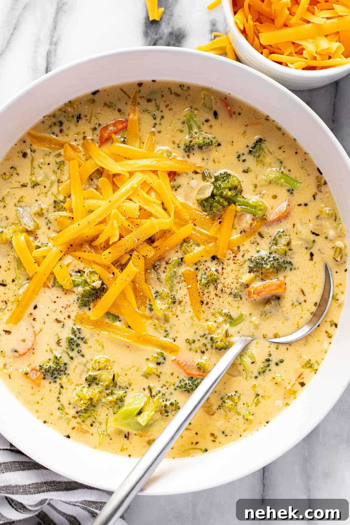 Creamy Instant Pot Broccoli Cheddar Soup Recipe 2 White bowl filled with homemade broccoli cheese soup topped with shredded cheddar.