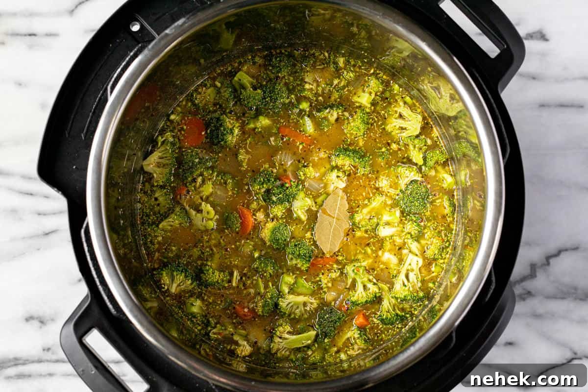 Creamy Instant Pot Broccoli Cheddar Soup Recipe 6 Instant pot filled with veggies, broth, and bay leaves.