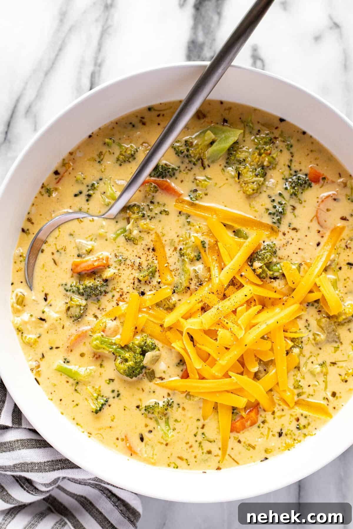 Creamy Instant Pot Broccoli Cheddar Soup Recipe 9 White bowl filled with homemade broccoli cheese soup topped with shredded cheddar.