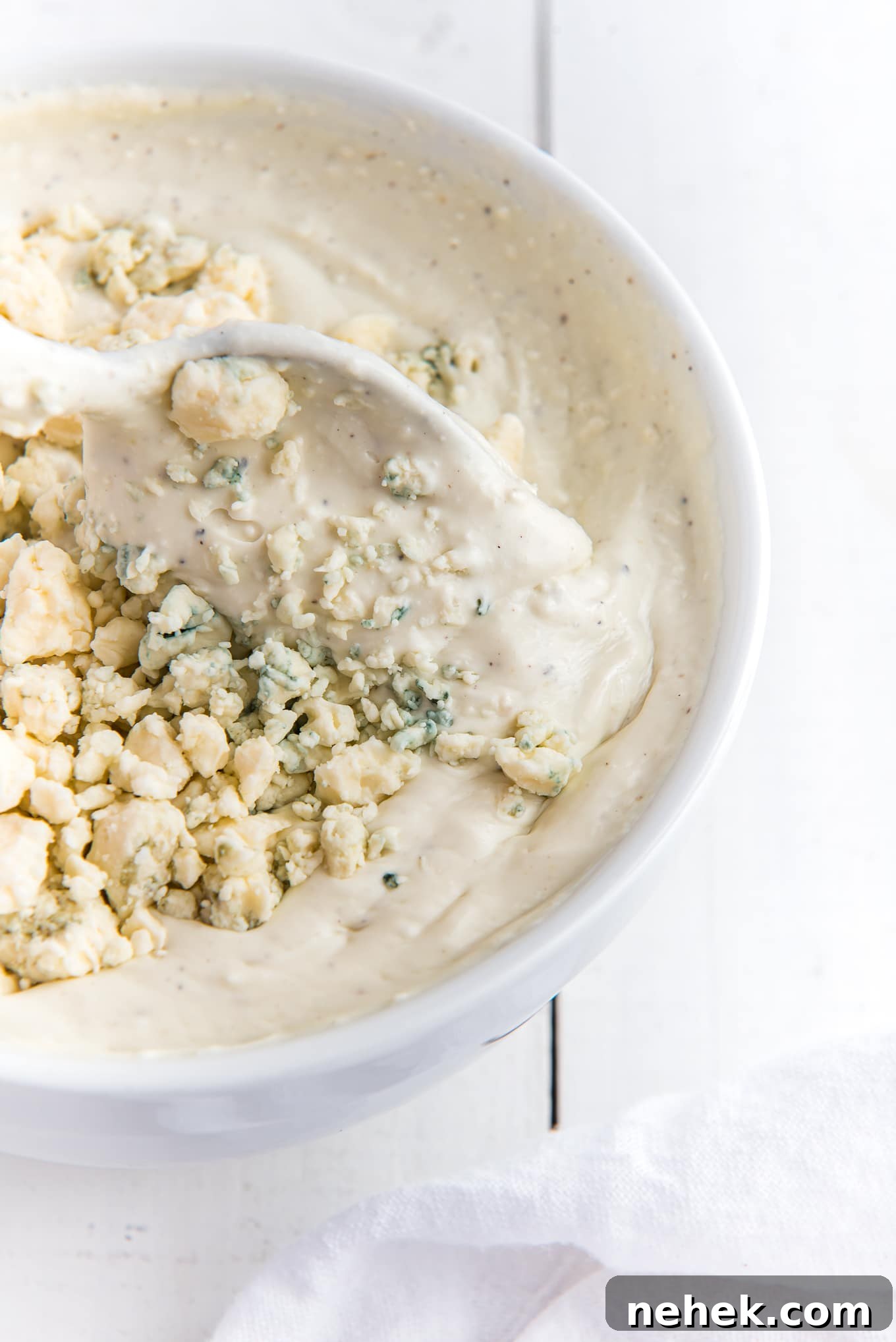 A spoon dipping into the bowl of dressing to take a serving out with crumbles on top.