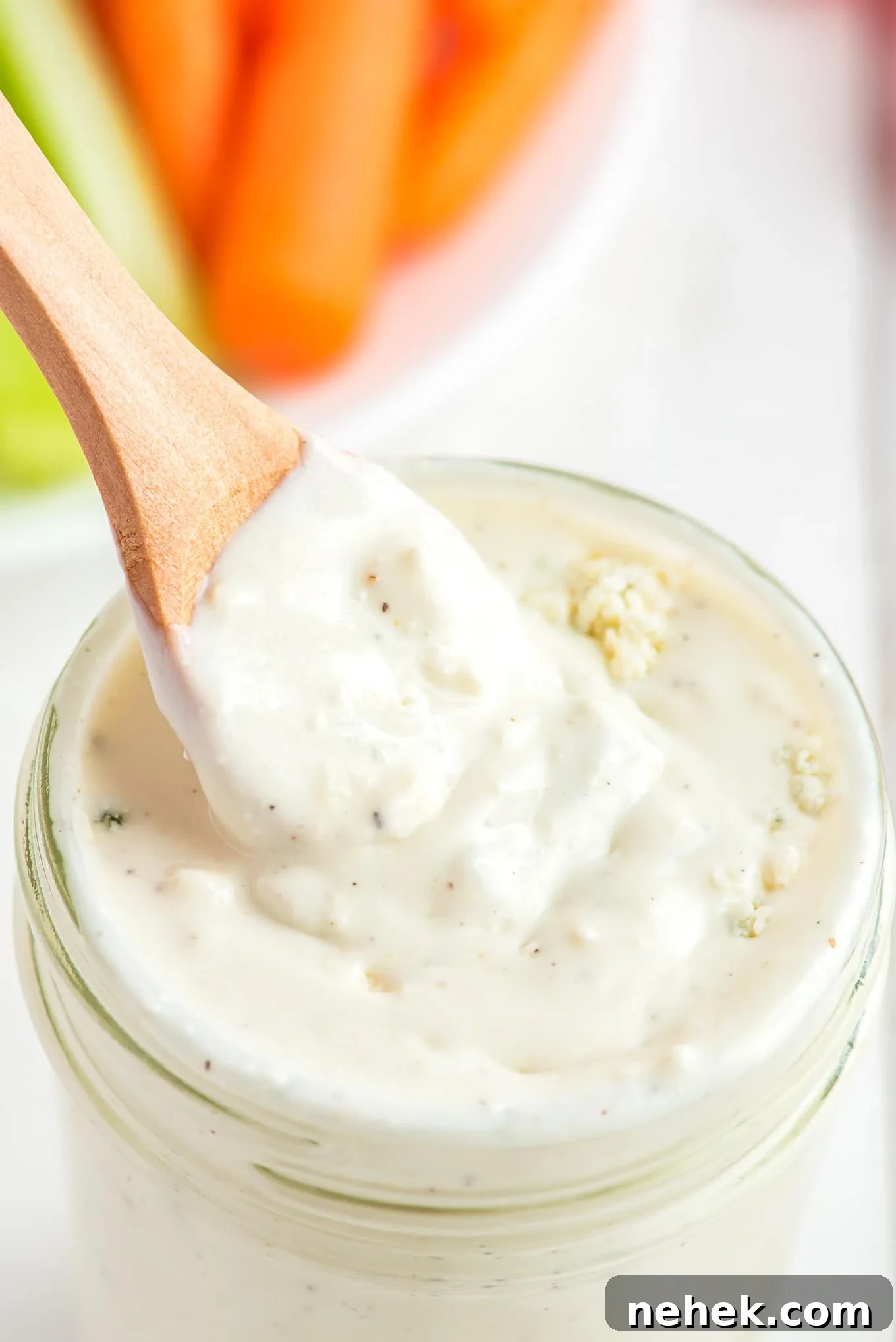 A jar of blue cheese dressing with a spoon dipping into it.