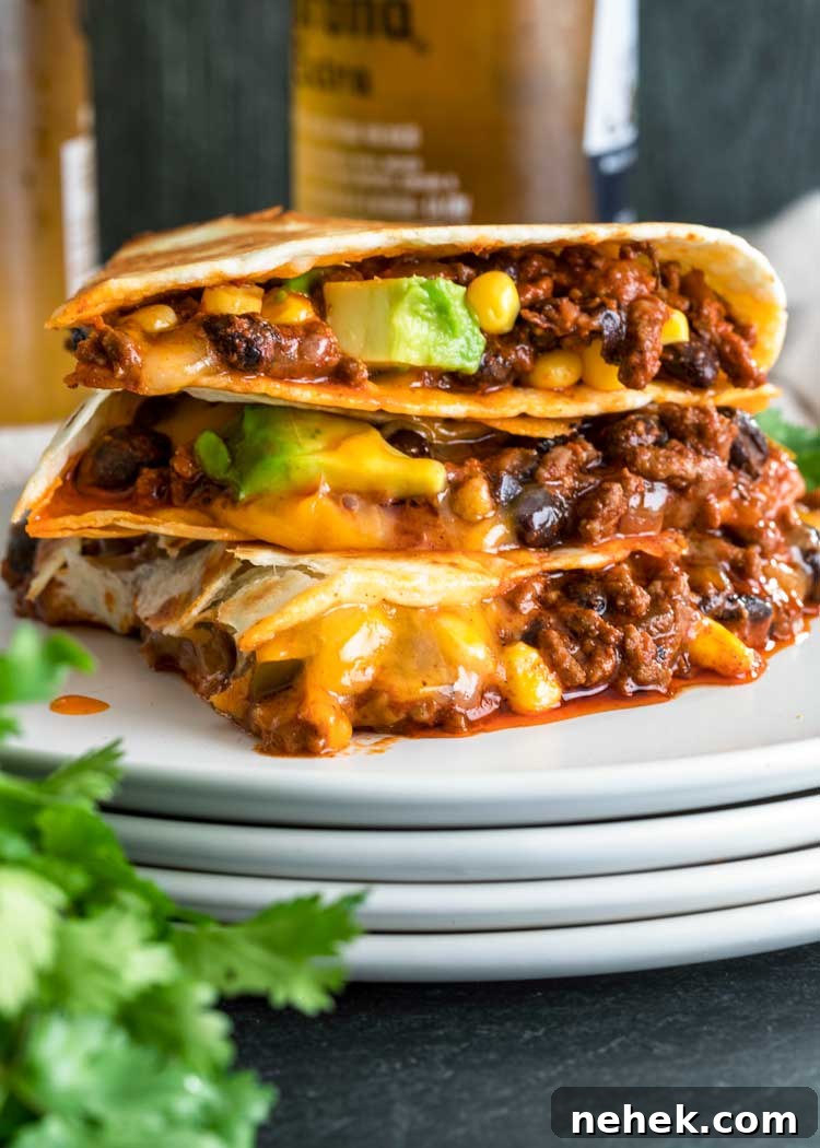 My Crispy Ground Beef Quesadillas are filled with melted Queso quesadilla, cheddar or Monterey Jack cheese, seasoned ground beef, avocado, beans and corn. stack of Crispy Ground Beef Quesadillas on white plate with beer