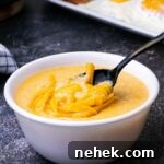 a bowl of cheese grits with a spoon digging in