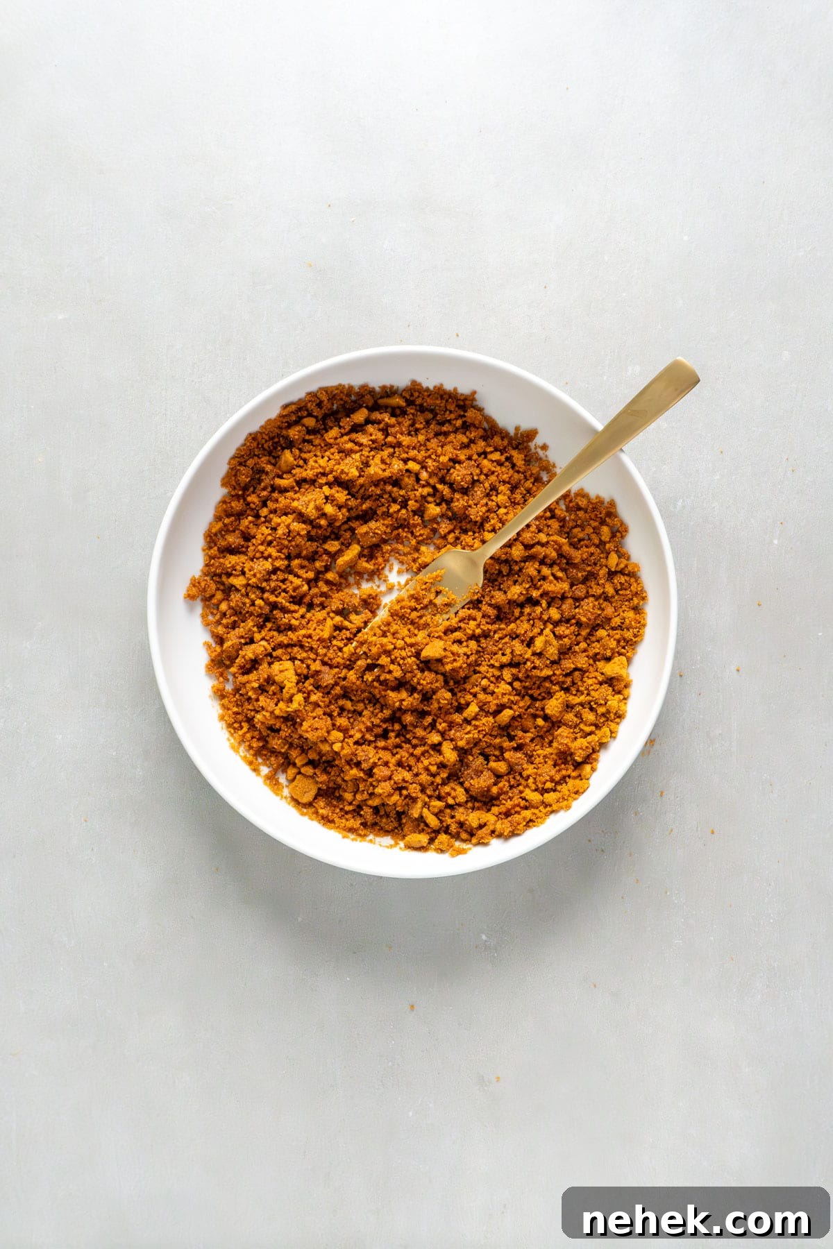 Ground Biscoff cookies in a small bowl mixed with melted butter.