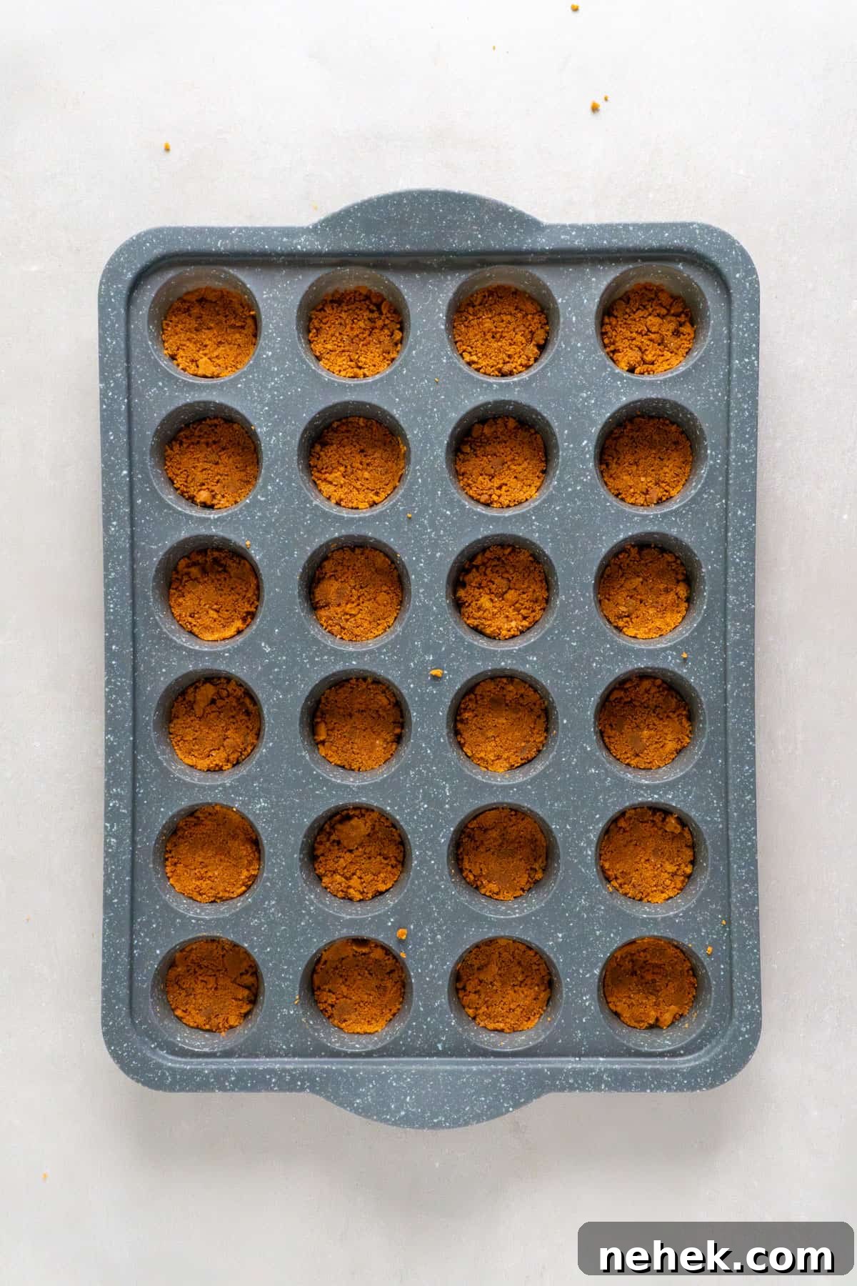 Biscoff cookie crust pressed into a mini muffin pan.