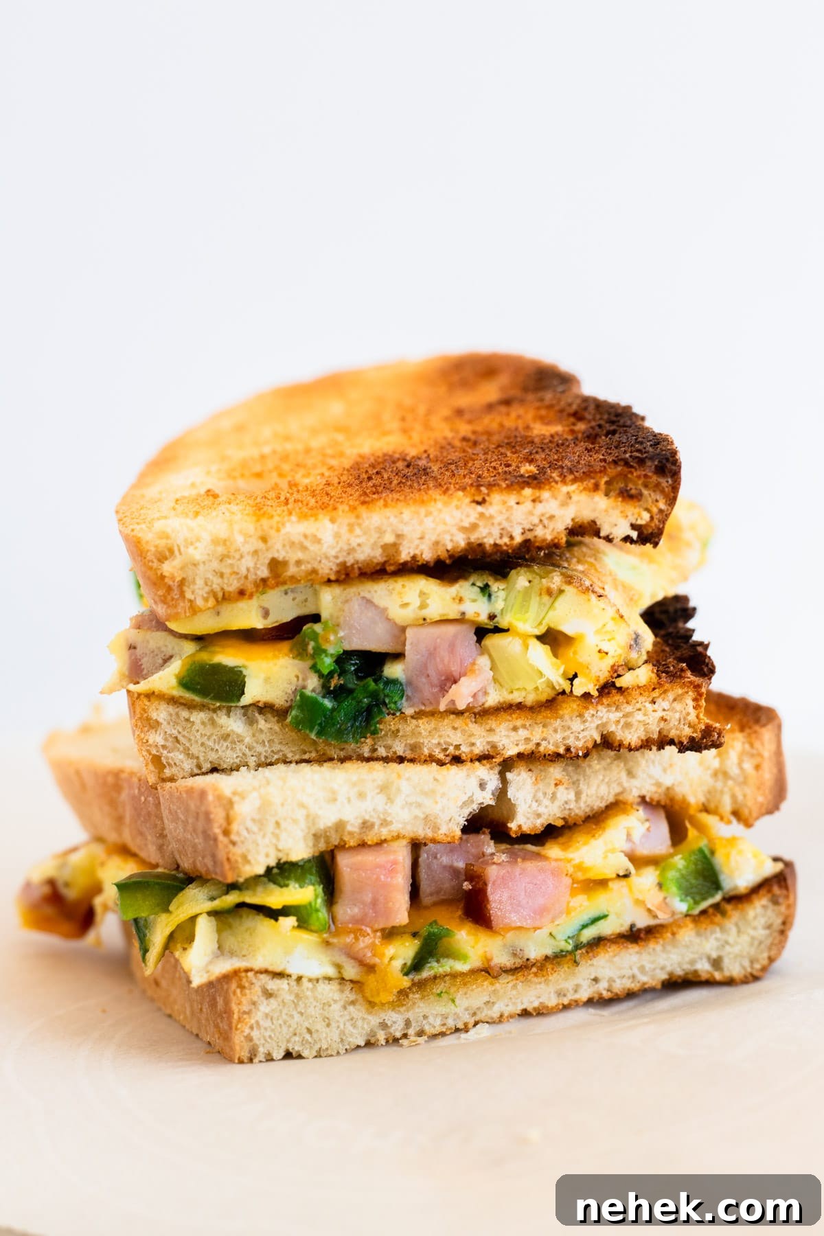 How to Make a Classic Western Sandwich (Ham, Egg & Peppers) 2 Two halves of a toasted western sandwich stacked on top of each other.