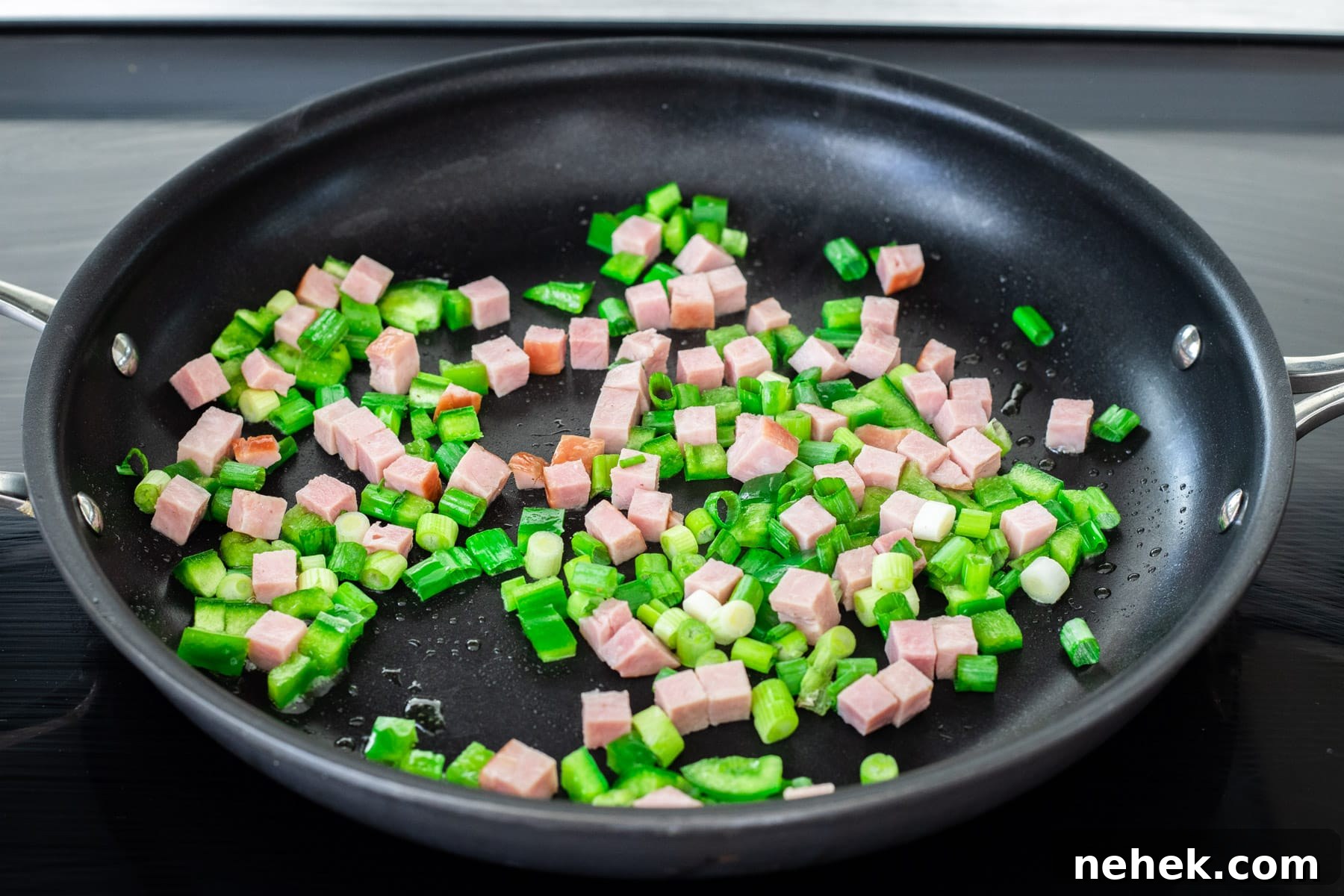 How to Make a Classic Western Sandwich (Ham, Egg & Peppers) 4 Ham, onion and green pepper sautéing in a skillet.