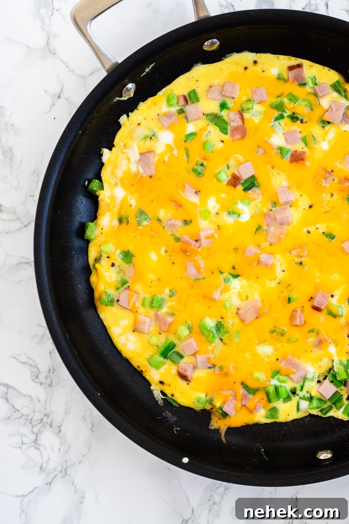 How to Make a Classic Western Sandwich (Ham, Egg & Peppers) 7 A top down view of a cooked western omelette with melted cheese on top of it.