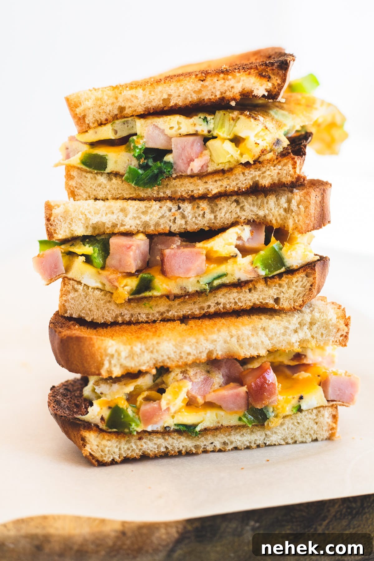 How to Make a Classic Western Sandwich (Ham, Egg & Peppers) 8 Three halves of a western sandwich stacked on top of each other.