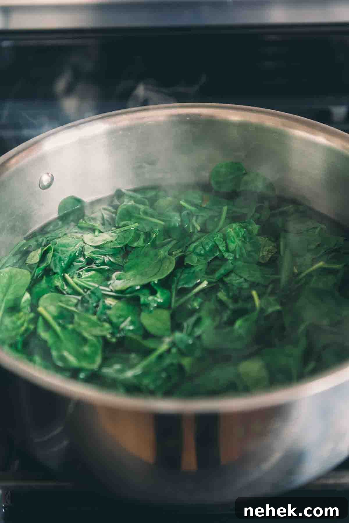Spinach being blanched in a pot of hot water.