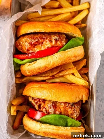 Two turkey burgers with fries in a parchment-lined tray, ready to serve.