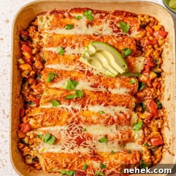 Ground turkey enchiladas topped with avocado in a brown baking dish.