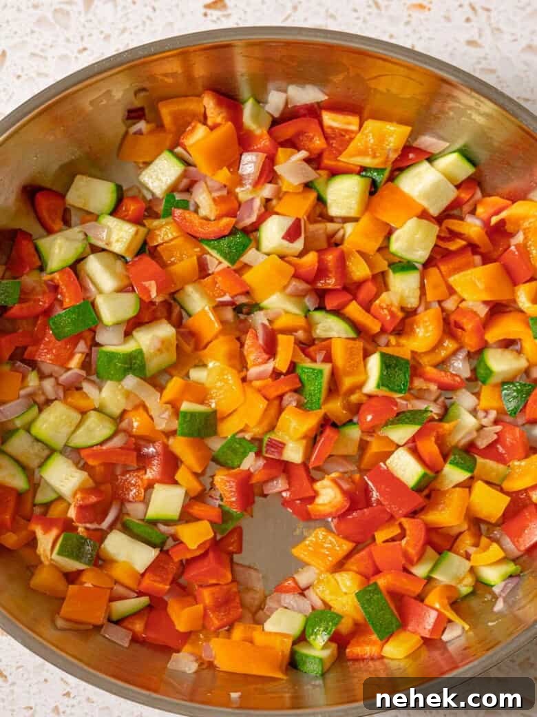 Diced onion, bell peppers and zucchini cooked in a skillet.