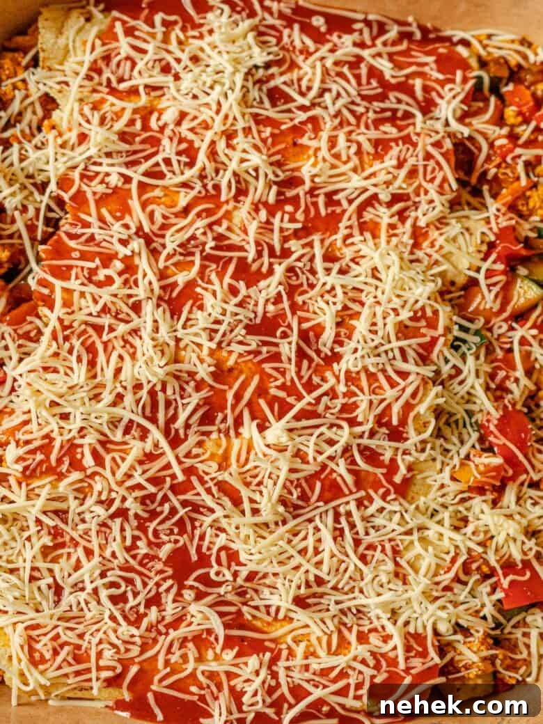 uncooked enchiladas in a casserole dish topped with shredded cheese