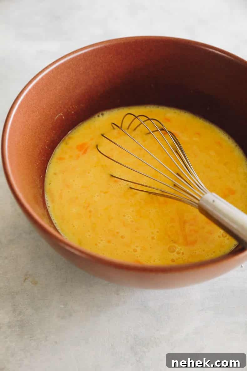 whisked eggs and milk in a brown bowl.