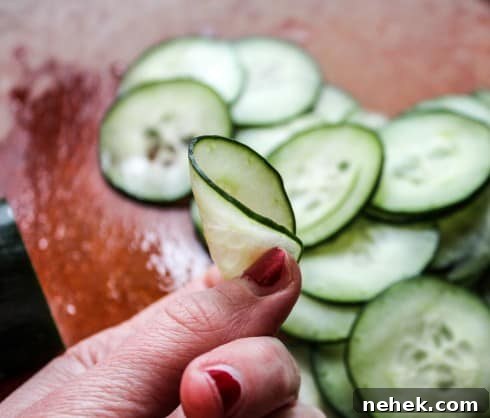 Zesty Mexican Cucumber Salad with Cilantro & Lime 2 hand showing flexibility of a thin cucumber slice.