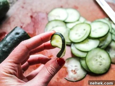 Zesty Mexican Cucumber Salad with Cilantro & Lime 3 hand showing the flexibility of a thin cucumber slice.