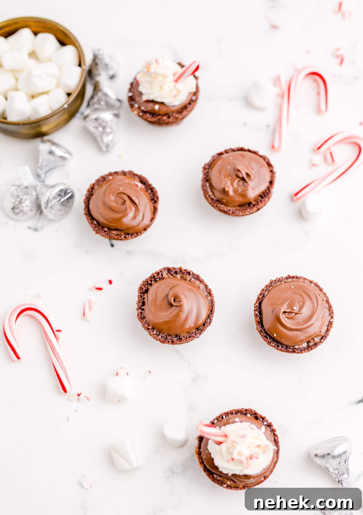 hot chocolate brownie bites laid out with a bowl of marshmallows and candy canes scattered around
