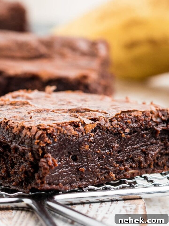 a close up of a moist banana brownie with a banana in the background