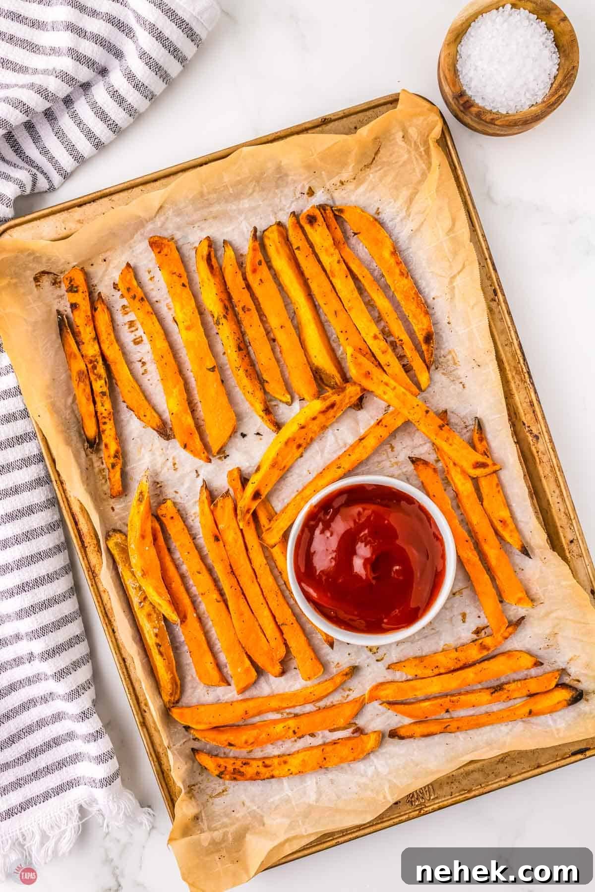 Crispy Oven-Baked Sweet Potato Fries Recipe 2 sweet potato fries on a baking sheet with ketchup