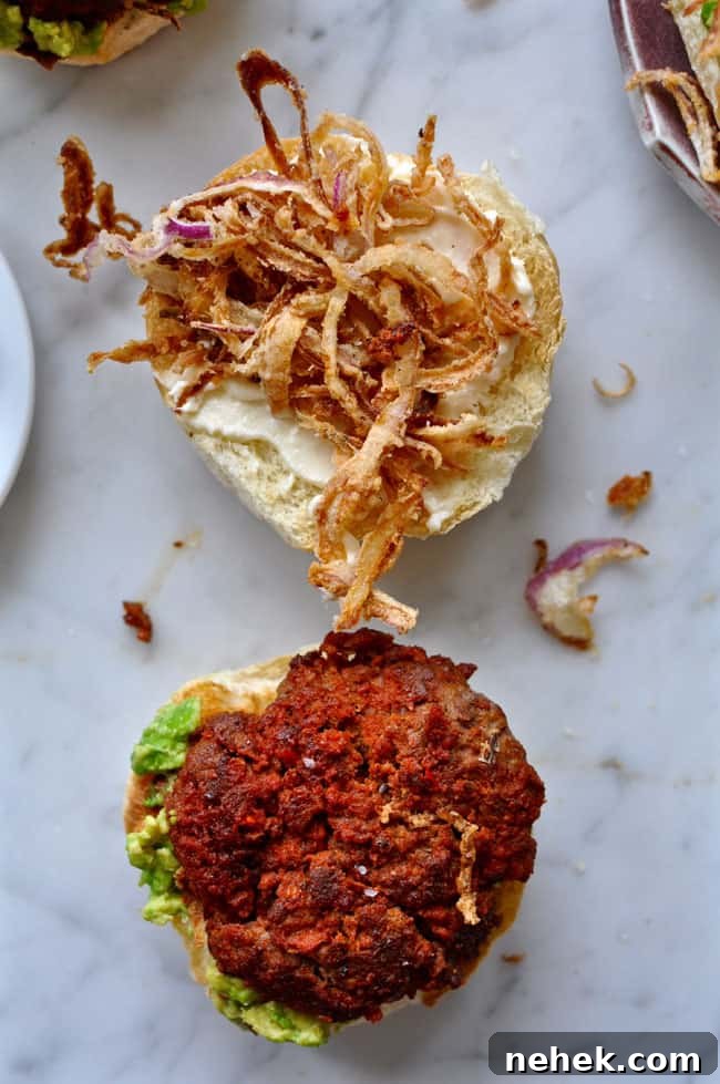 These chorizo burgers are made with Mexican chorizo and ground beef then topped with smashed avocado and a generous pile of crispy fried red onion strings. chorizo burgers with smashed avocado and crispy onions recipe