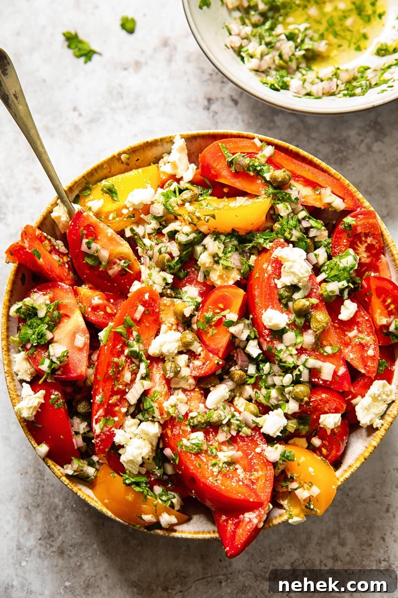 top down view of tomato salad in a bowl and herb vinaigrette in a smaller bowl