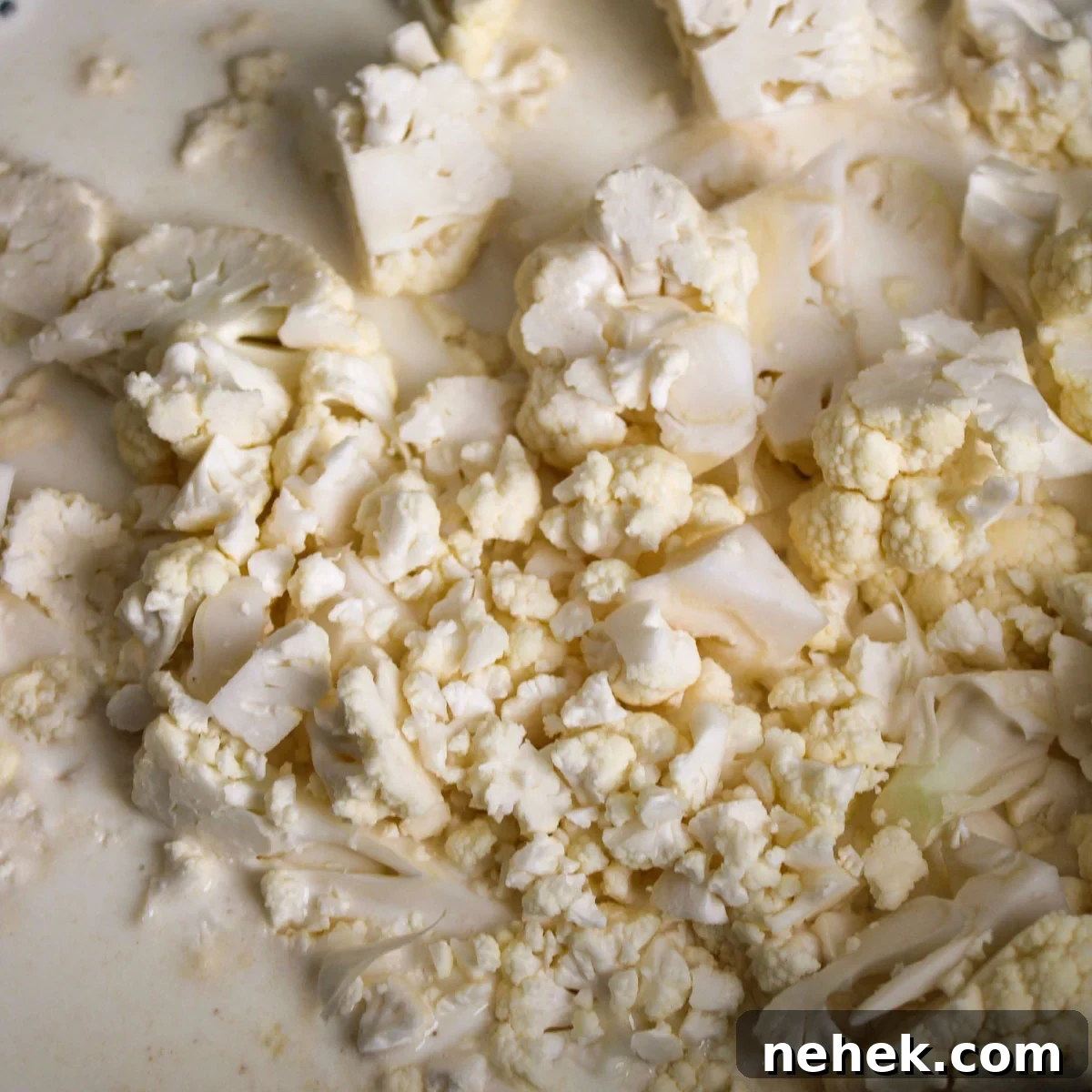 Chopped cauliflower boiling in the half and half and chicken broth.