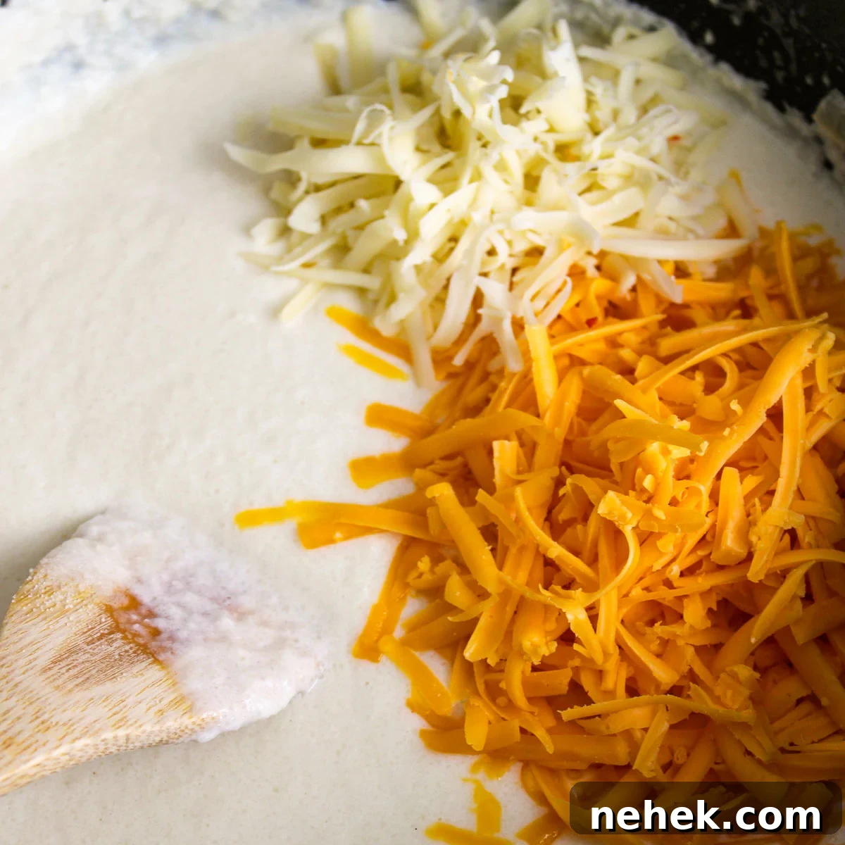 Adding the pepper jack cheese, sharp cheddar cheese, and dijon mustard to the blended cauliflower soup.