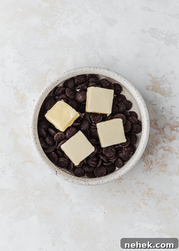 A white bowl of chocolate and butter on a white counter.