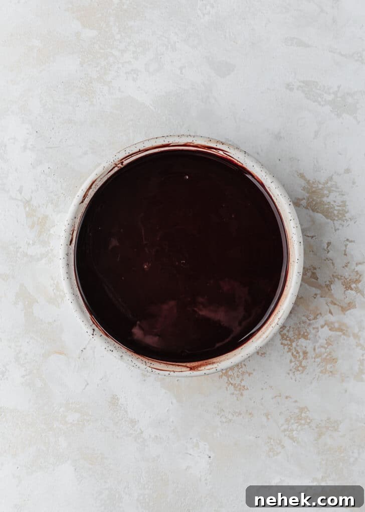A white bowl of melted chocolate on a white table.