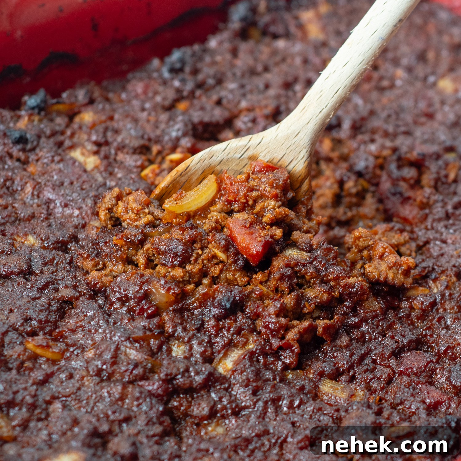Sweet and Spicy Sloppy Joe Tacos with Lime Sour Cream 7 the meat in a baking pan with a wooden spoon lifting some up.