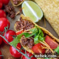 Sweet and Spicy Sloppy Joe Tacos with Lime Sour Cream 10 close up of beef taco with tomatoes, cheese, and lettuce
