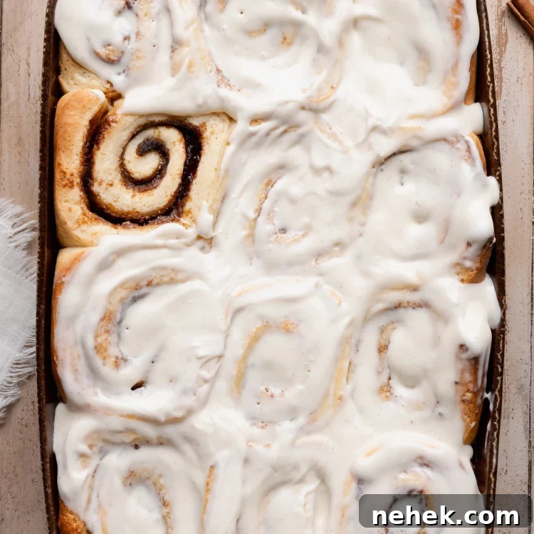 Overhead view of soft overnight cinnamon rolls baked in a ceramic baking dish