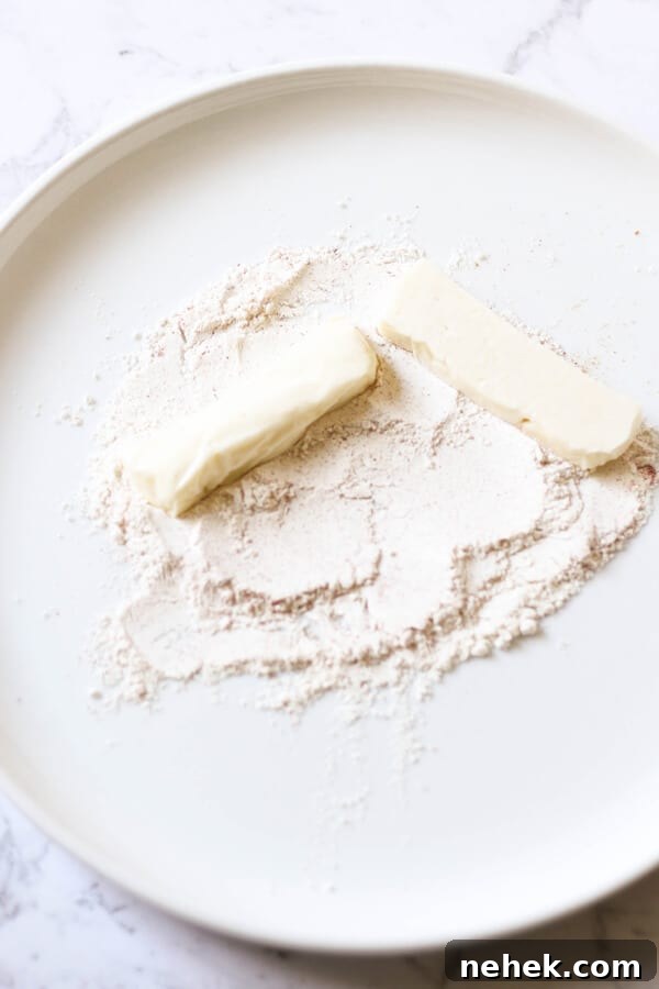 halloumi slices being covered in flour on a white plate.