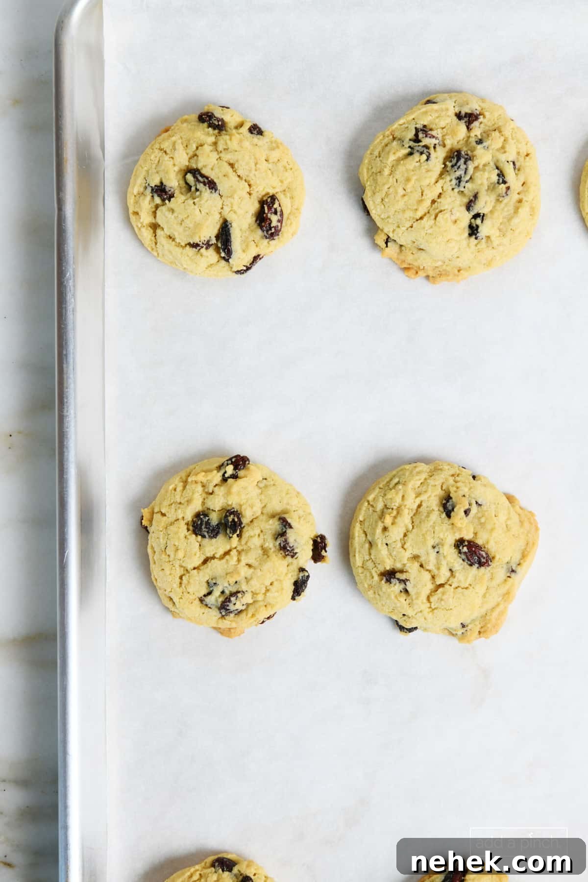 Freshly baked oatmeal raisin cookies on a baking sheet.