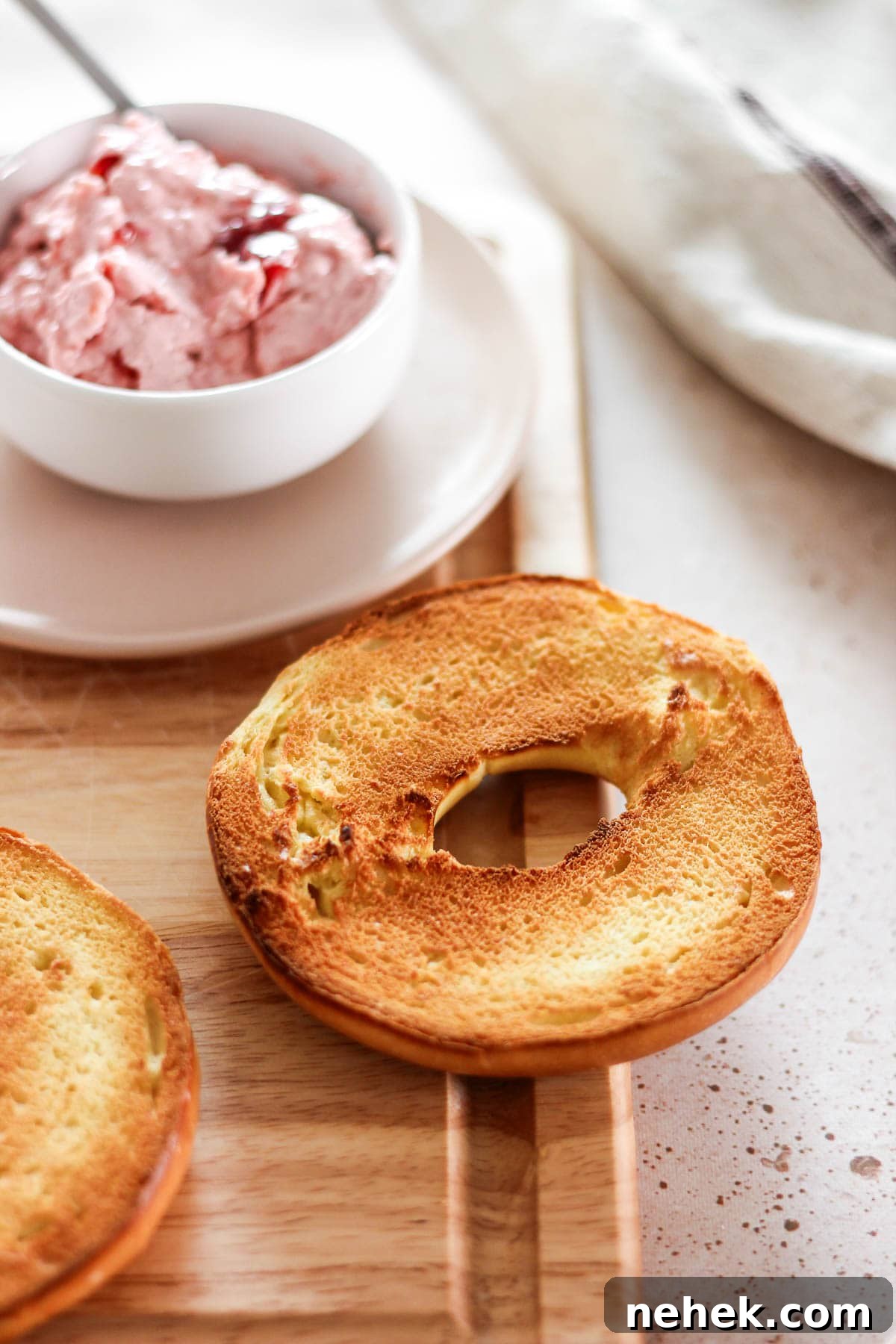Homemade strawberry cream cheese spread in a small bowl with bagels on the side.