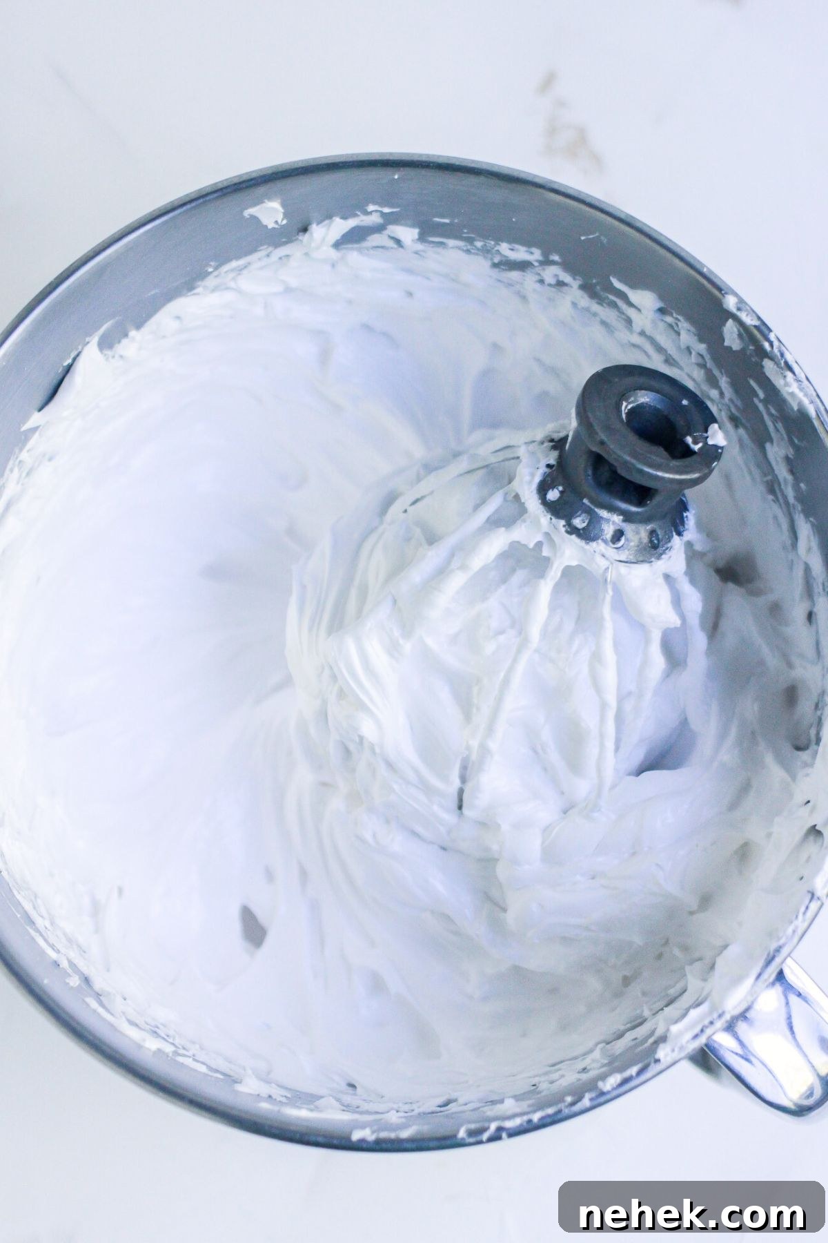 Meringue Christmas Tree Cookies: Festive Dessert Recipe Ideas 4 Egg whites, sugar, and other ingredients, mixed until thick and soft peaks form, in a silver mixing bowl.