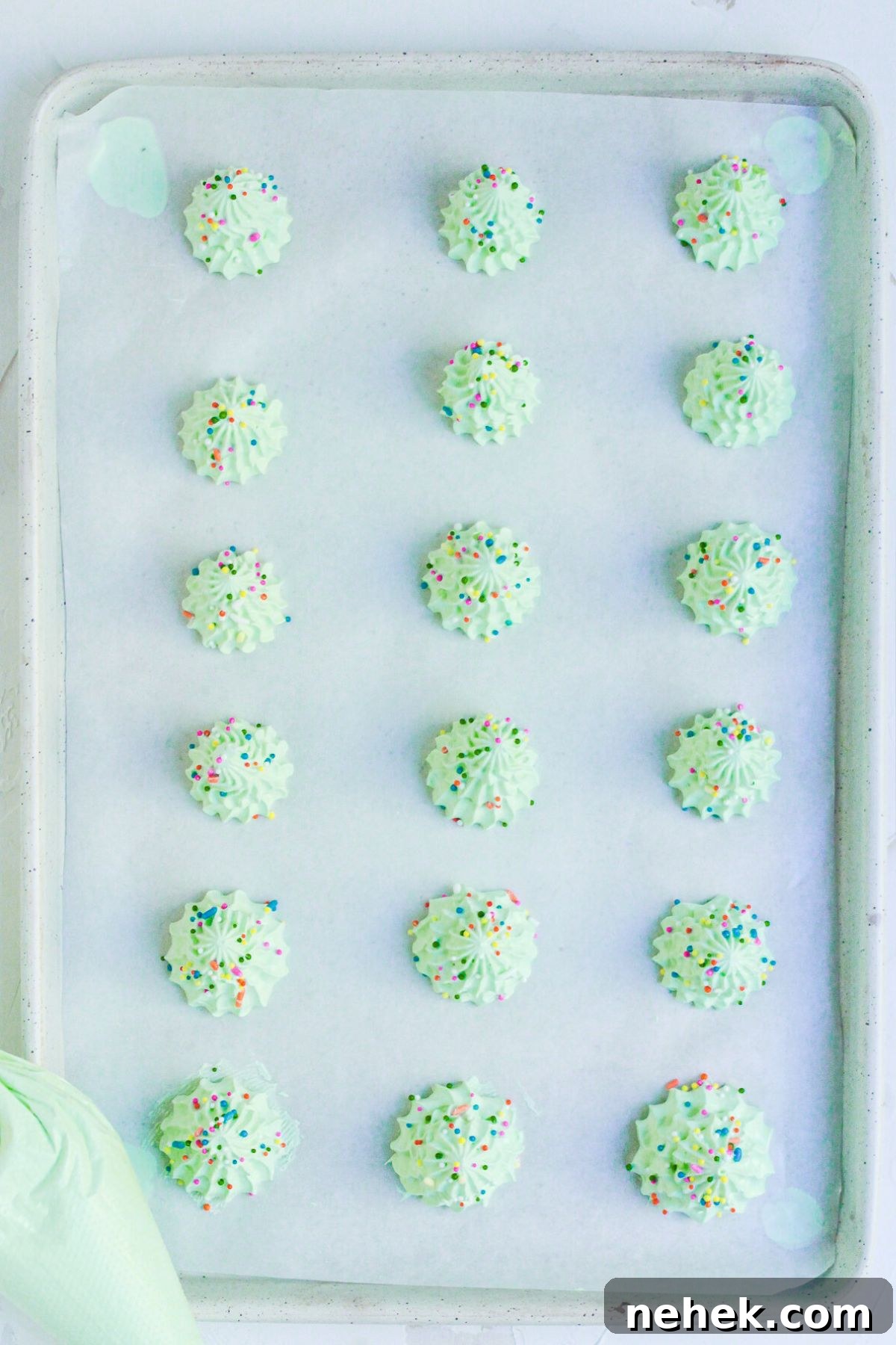 Meringue Christmas Tree Cookies: Festive Dessert Recipe Ideas 6 Mini trees piped onto baking sheet, lined with parchment paper and then decorated with sprinkles.