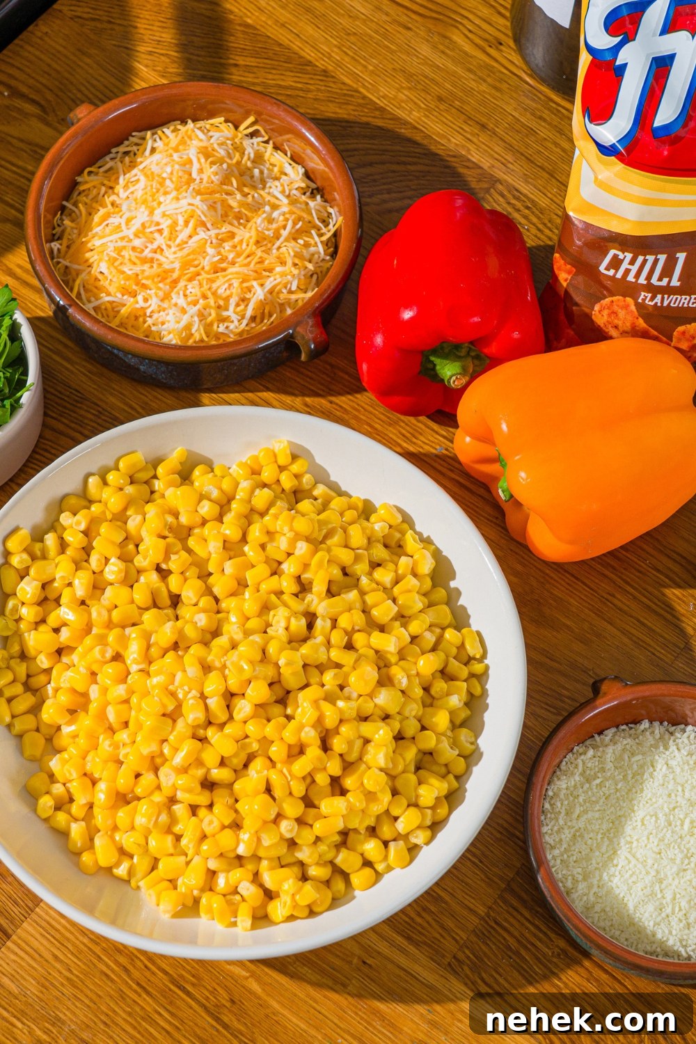 Spicy Corn Salad with Chili Cheese Fritos Crunch 4 A wooden counter with ingredients to make corn salad with chili cheese fritos including corn, red and yellow bell pepper, shredded cheese, and chili cheese fritos.