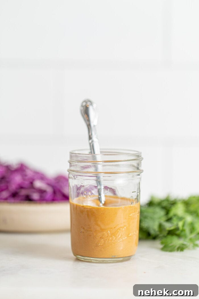 Jar of peanut sauce with a spoon resting in it.