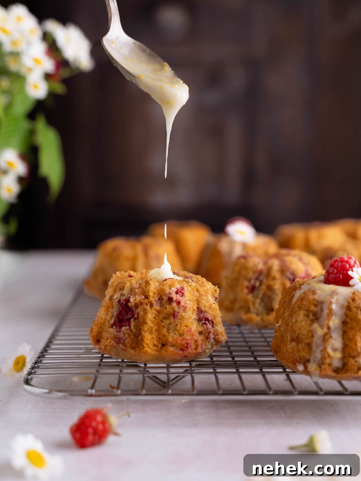 Raspberry and Chamomile Tea Cakes with Lemon Glaze 3 Lemon glaze dripping off a spoon onto a mini bundt cake